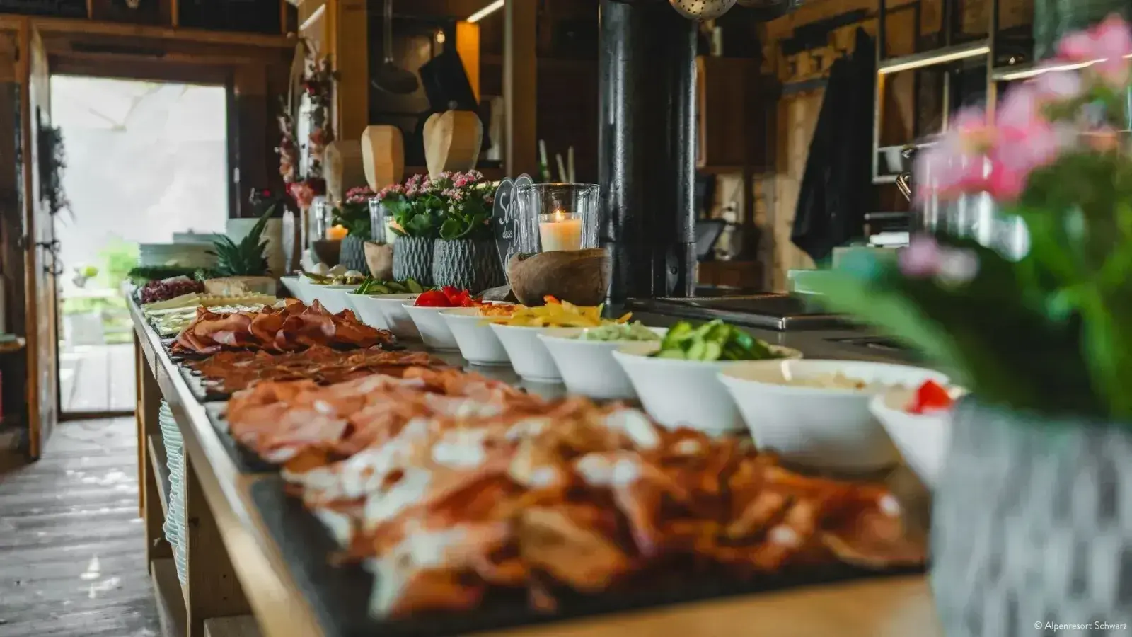 Frühstücksbuffet der Stöttlalm mit Aufschnitt, Schinken und Kerze in der gemütlichen Almstube