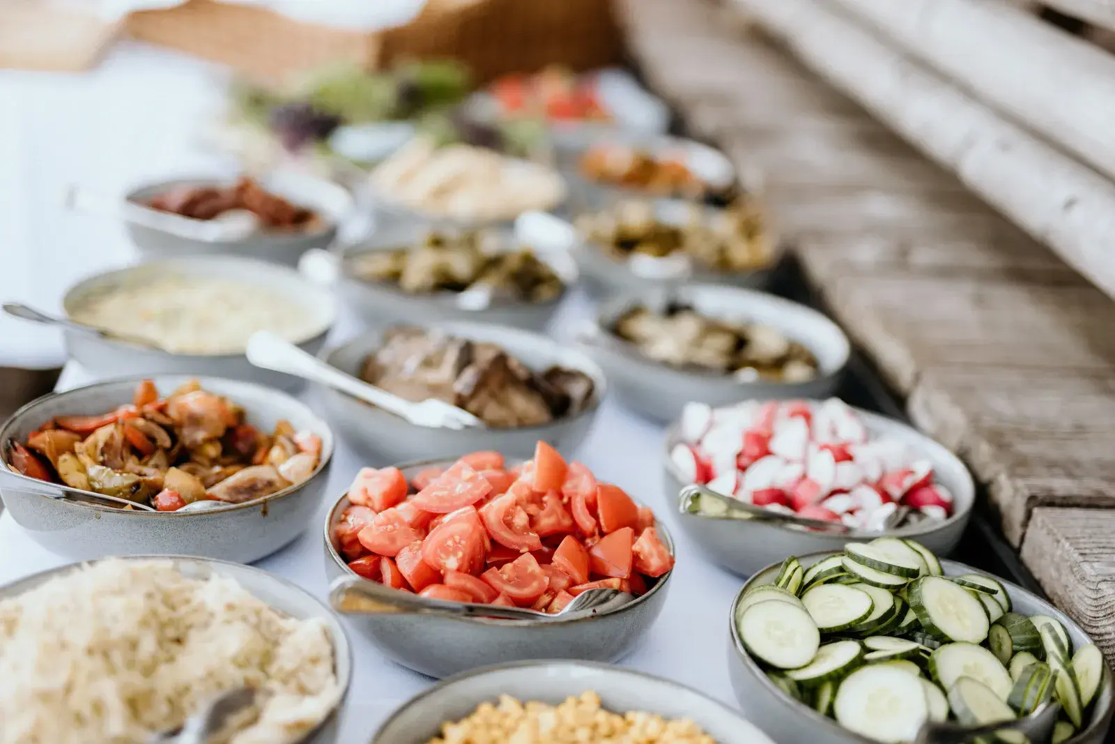 Reichhaltiges Salatbuffet mit frischen Tomaten, Gurken und Antipasti auf der Holzterrasse der Stöttlalm